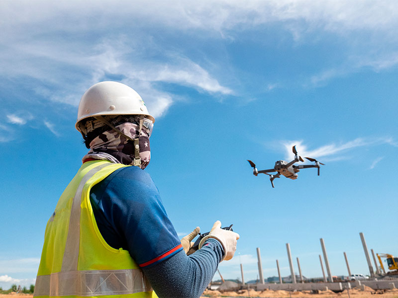construtor pilotando drone em construção