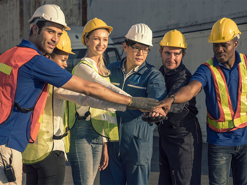 equipe de trabalhadores de uma construção civil amontoando as mãos em sinal de colaboração